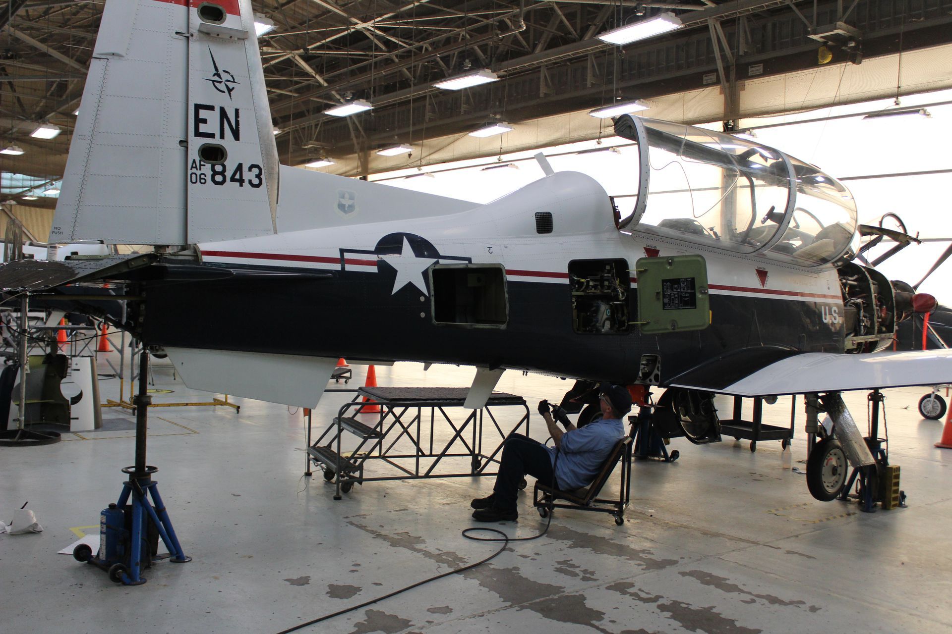A man sits in a chair in front of a plane with the letters en on the tail