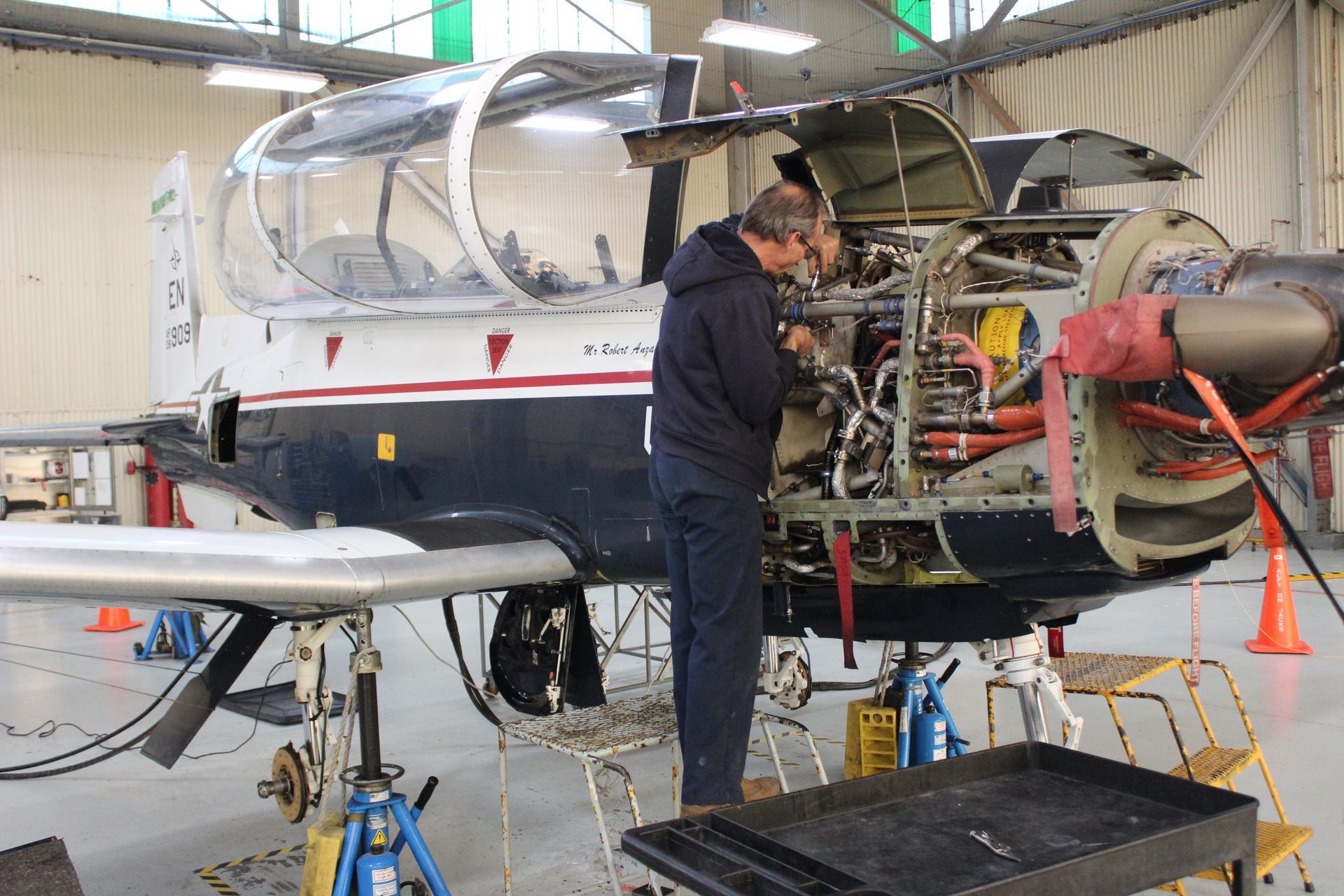 A man is working on an airplane in a hangar