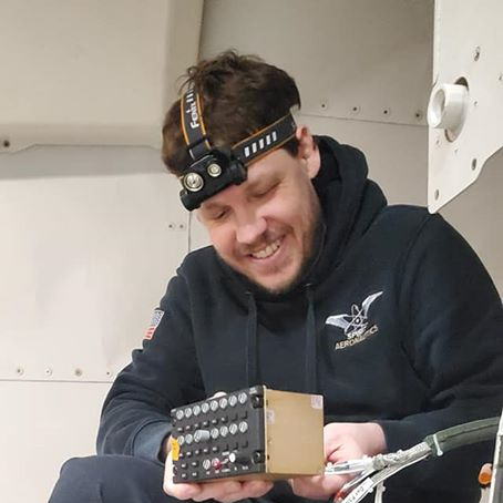 A man wearing a head light is holding a box