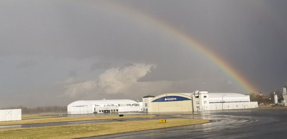 A rainbow is visible over a building on a cloudy day