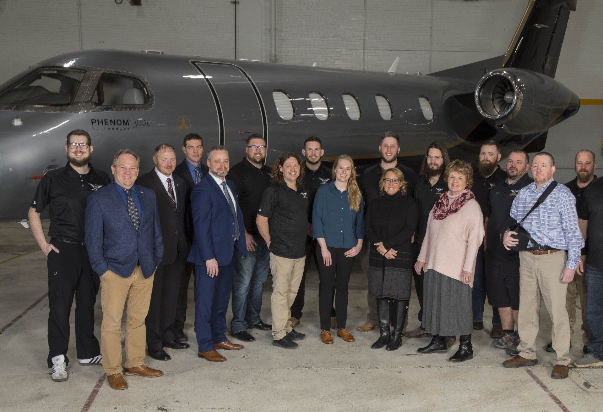 A group of people are posing for a picture in front of a plane.