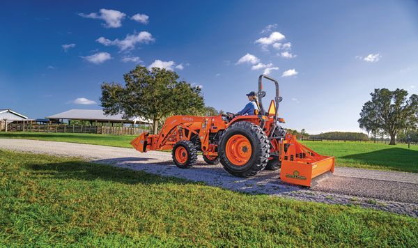 A construction worker is standing in front of a yellow excavator on a construction site.