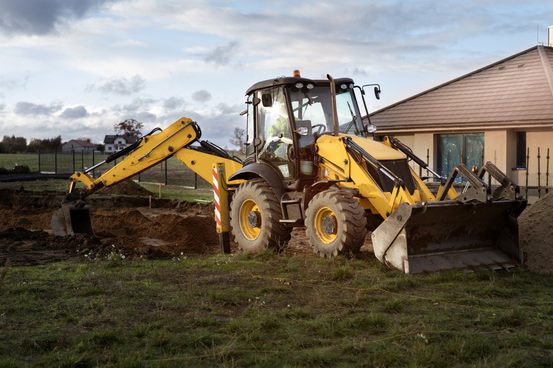 Excavator in front of beige house | Birch Run, MI | Duane Jones Excavating