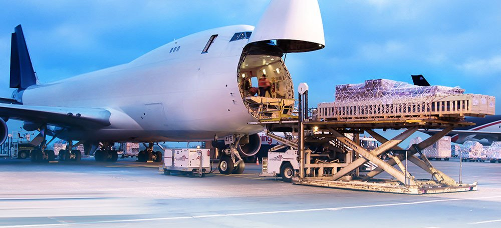 Workers load cargo onto an OVS Logistics plane. Trucks and workers are on the tarmac.