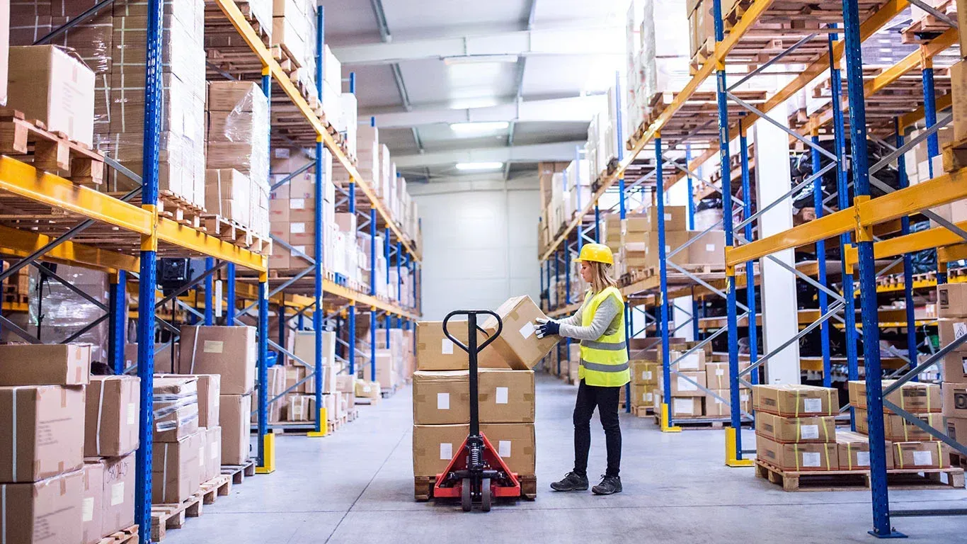 A man is loading boxes on a hand truck in a warehouse.