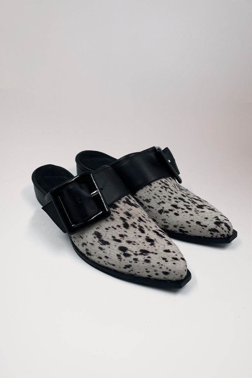 Un par de zapatos con estampado de leopardo y hebilla negra sobre una superficie blanca.