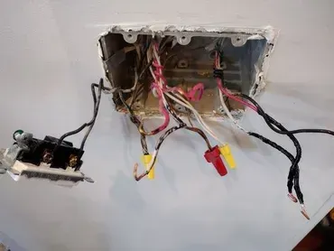 Electrical wiring inside a wall box with wire connectors and a light switch on the left.