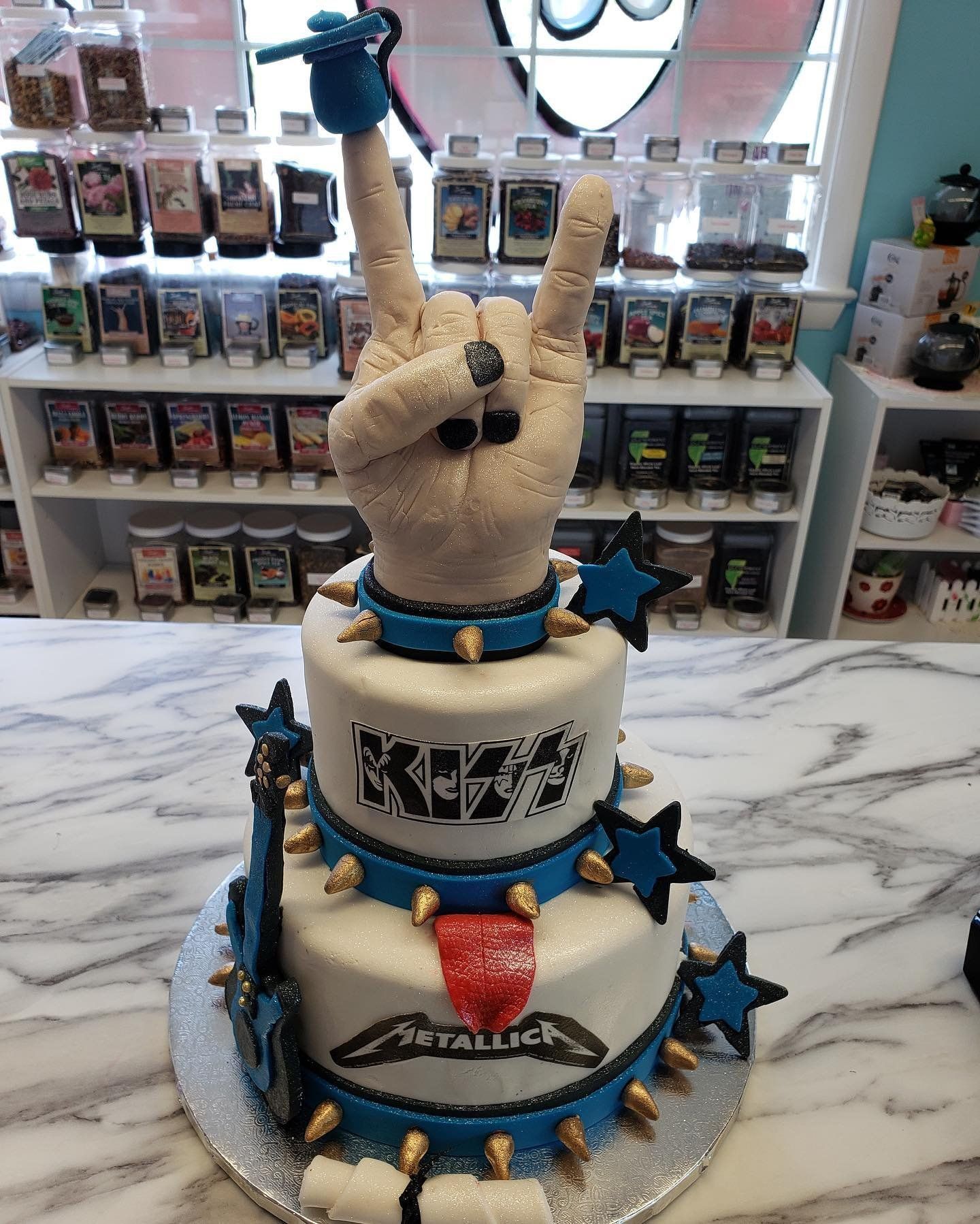 A cake with a hand making a rock and roll sign on top of it.