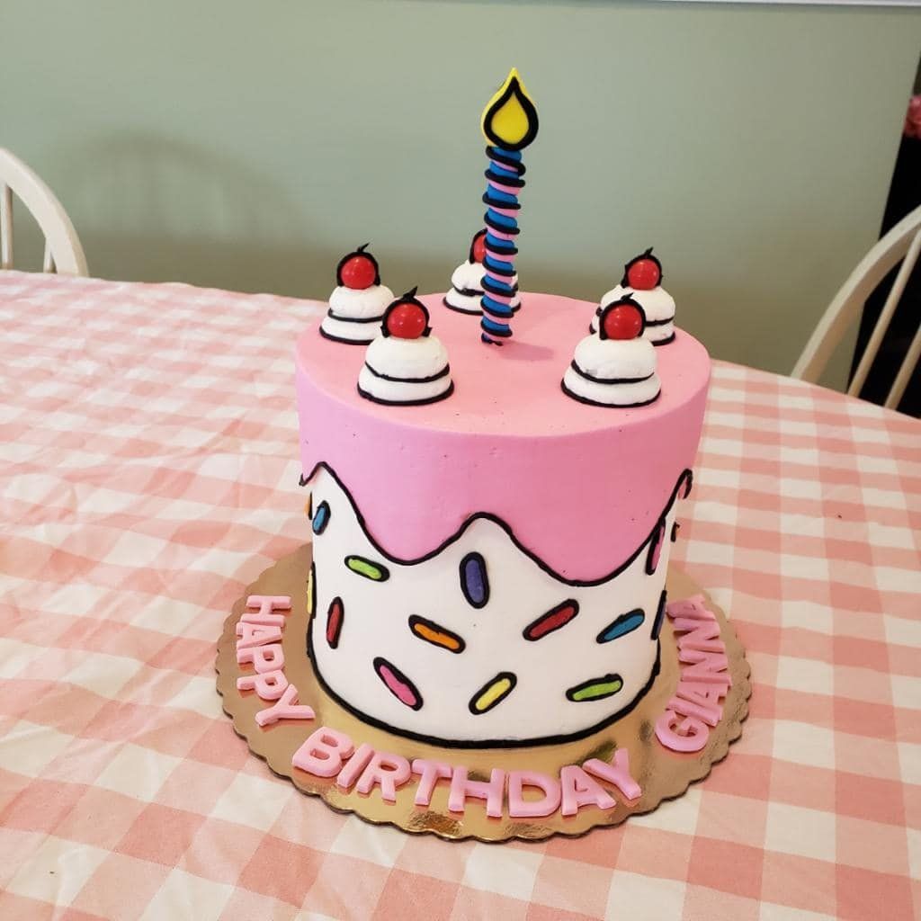 A pink and white birthday cake with a candle on top