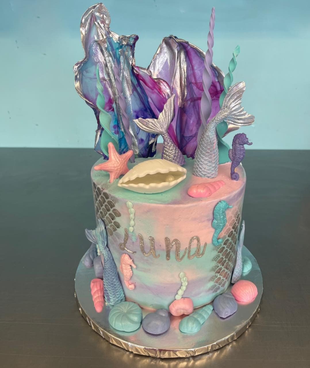A cake with a mermaid theme and the name luna on it