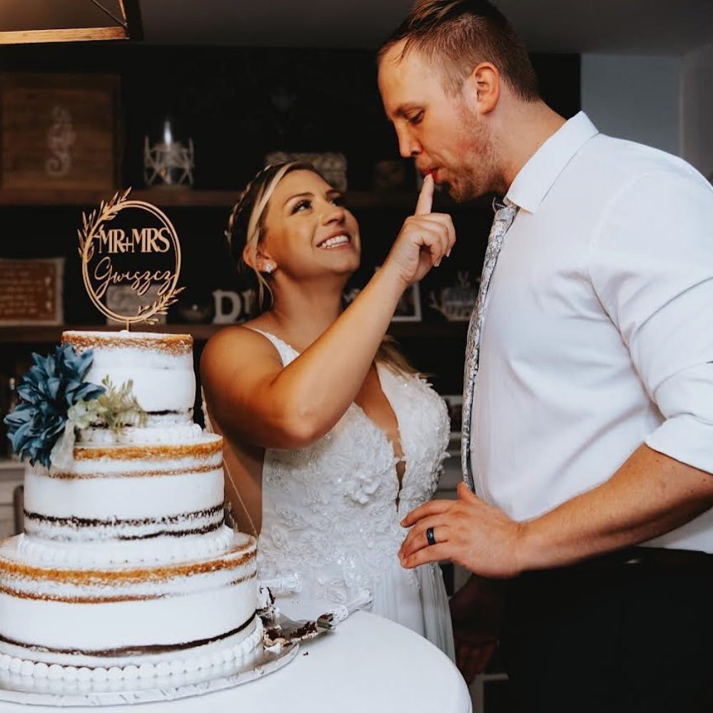 A bride and groom are cutting their wedding cake with a topper that says mr. and mrs.