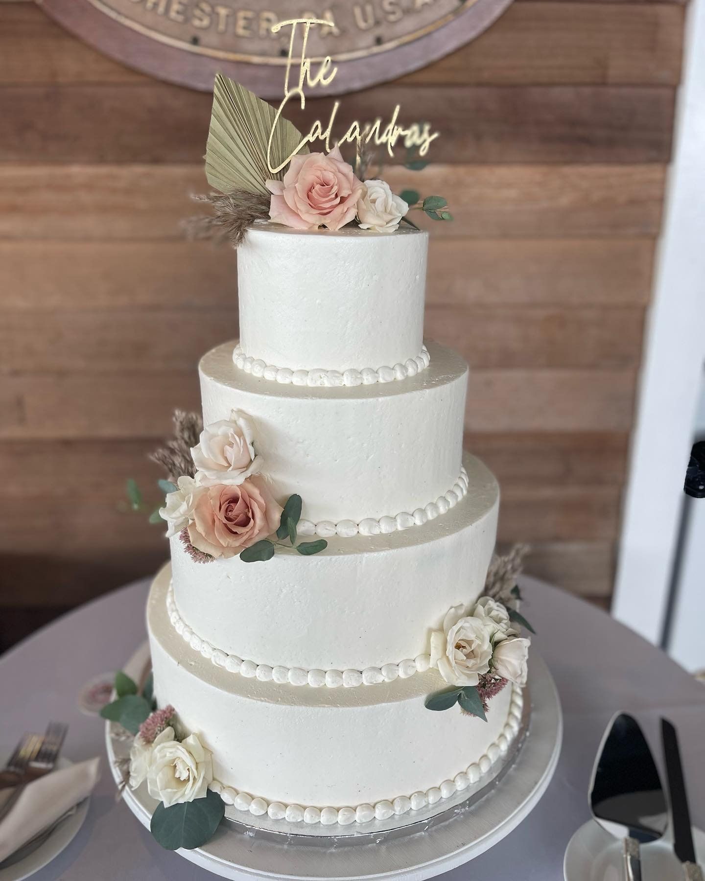 A white wedding cake with flowers on top is sitting on a table.