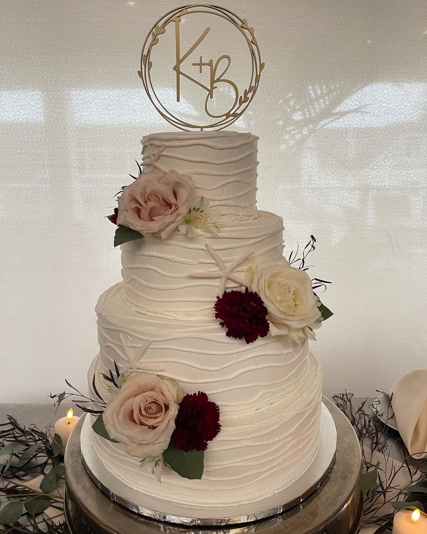 A wedding cake with flowers and a monogram on top is sitting on a table.