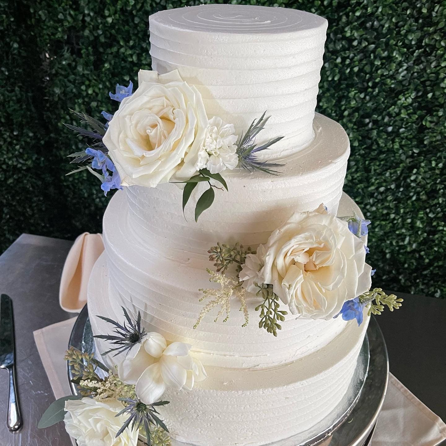 A white wedding cake with flowers on it is sitting on a table.