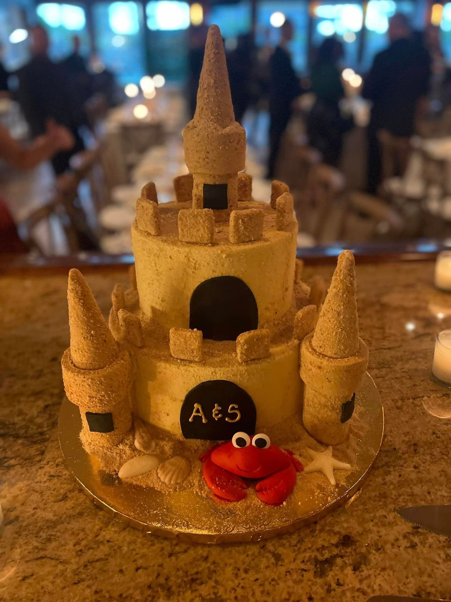 A cake in the shape of a sand castle with a crab on top