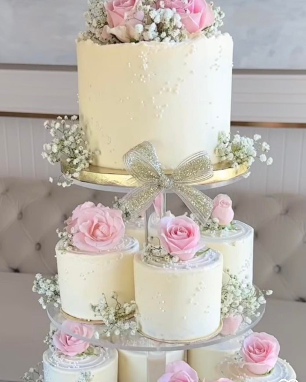 A stack of wedding cakes decorated with pink roses and baby 's breath.