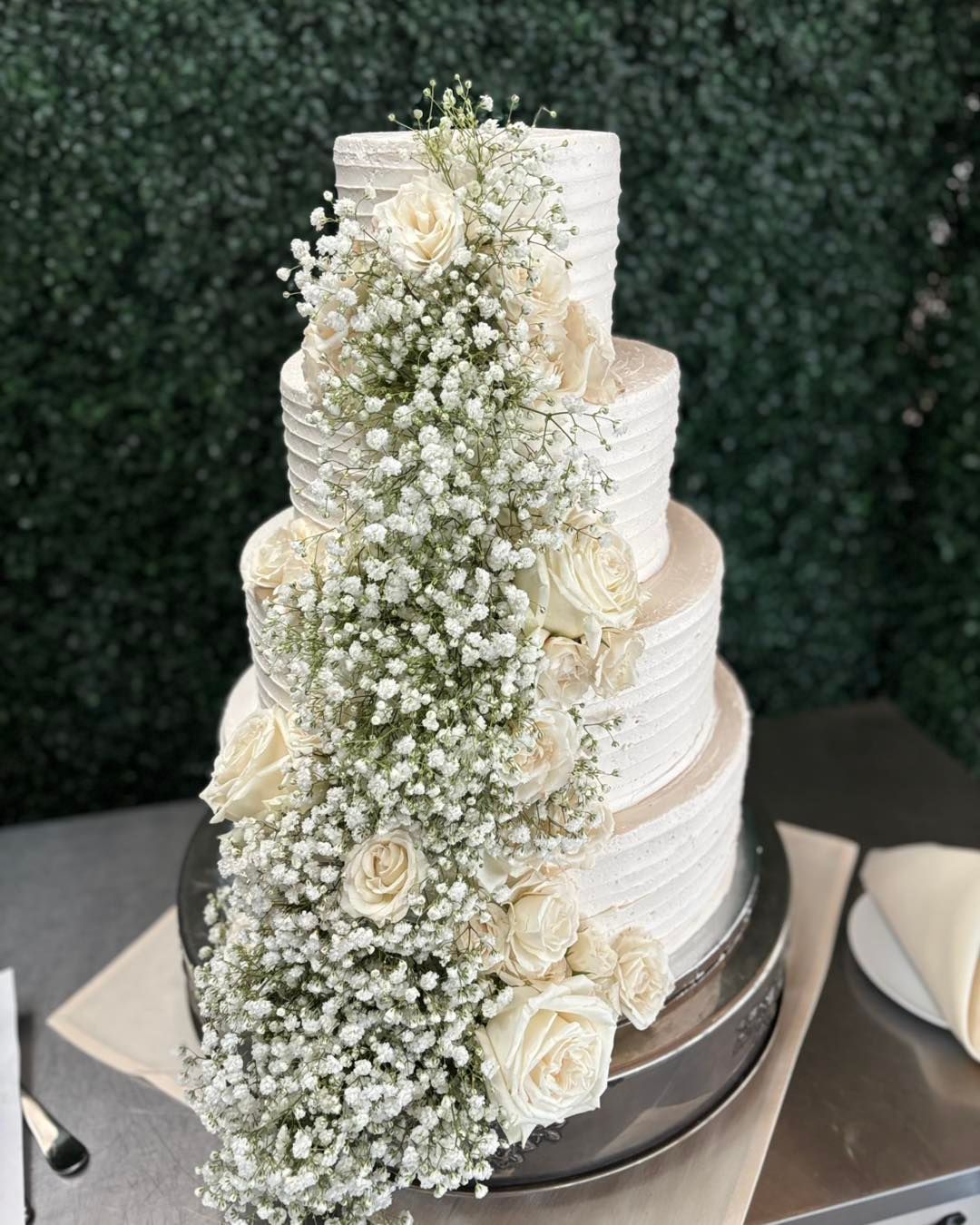 A wedding cake with baby 's breath and roses on it
