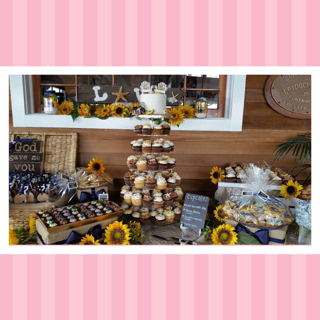 A table topped with cupcakes , cookies , and sunflowers.