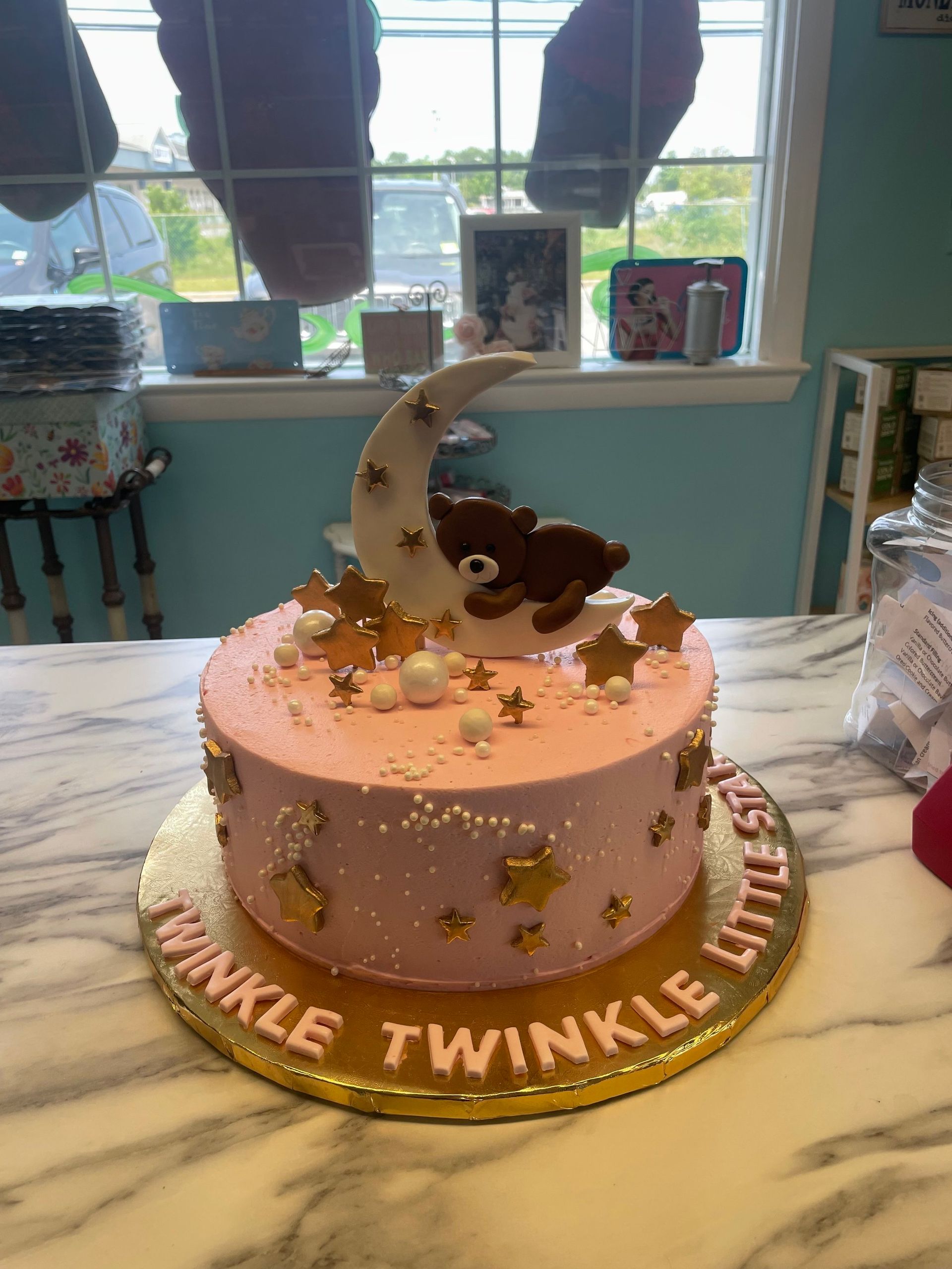 A pink cake with a teddy bear on top of it is sitting on a table.
