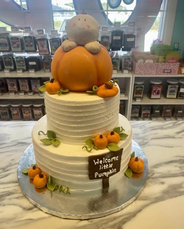 A baby shower cake with a pumpkin on top of it.