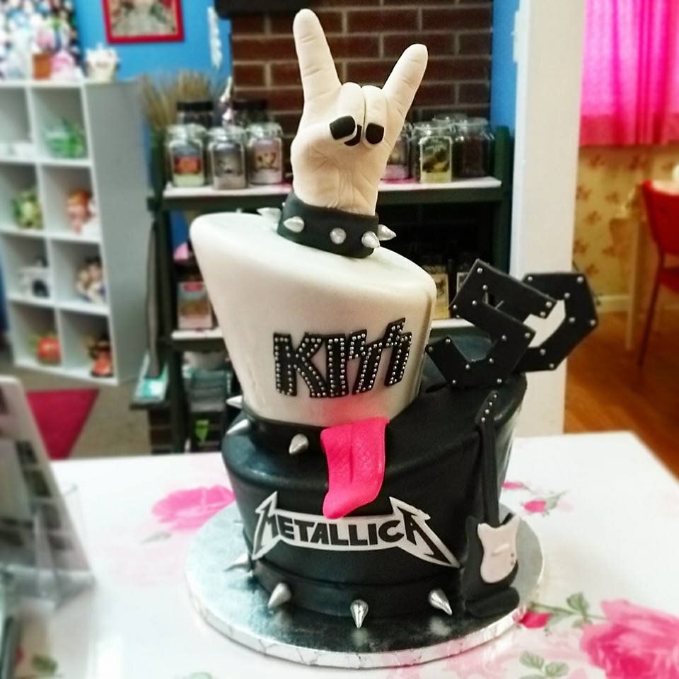A black and white cake with metallica written on it