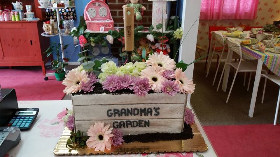 A cake with flowers in a box that says grandma 's garden