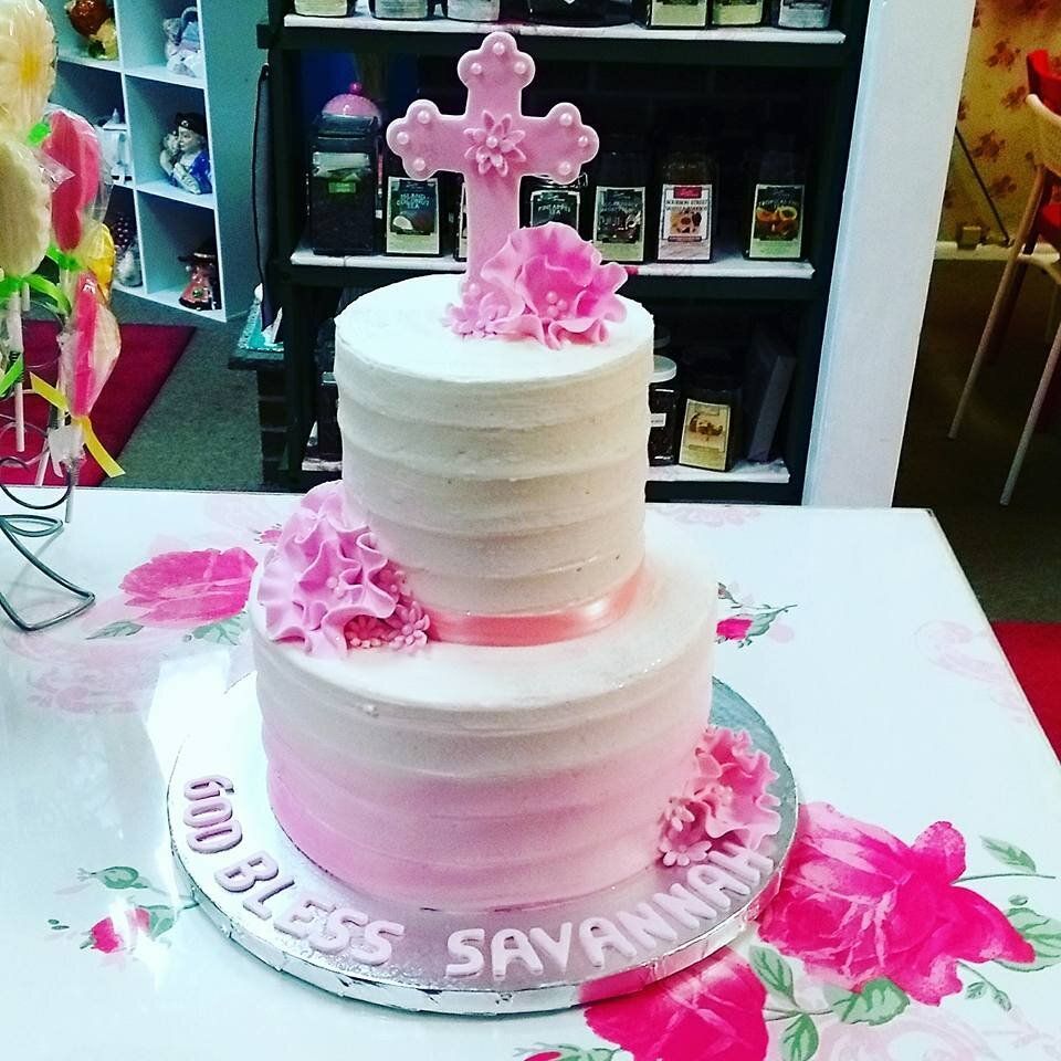 A pink and white cake with a cross on top of it