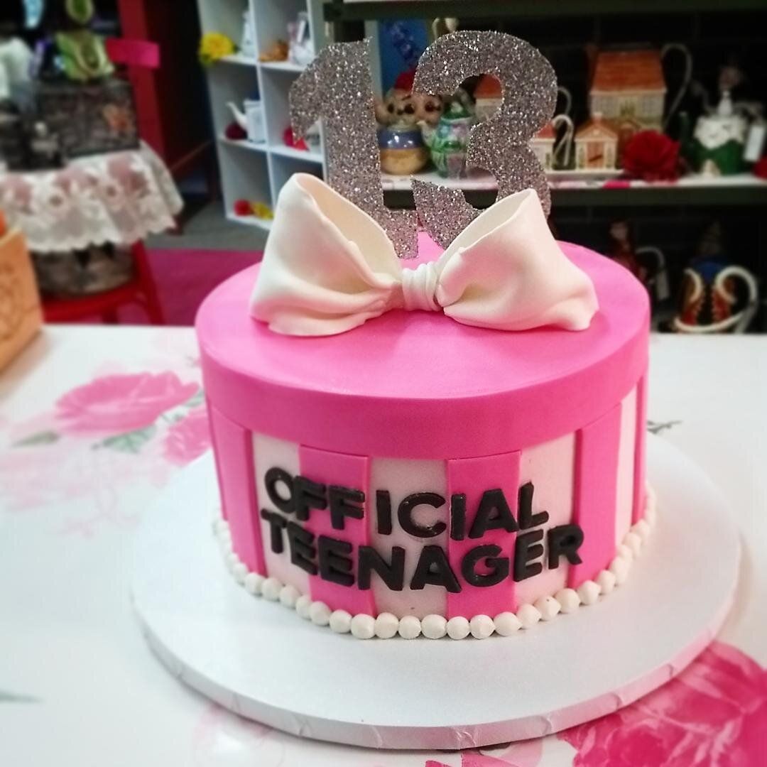 A pink cake that says official teenager on it