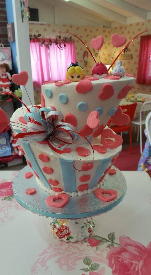 A cake in the shape of a teacup with hearts on it is on a table.