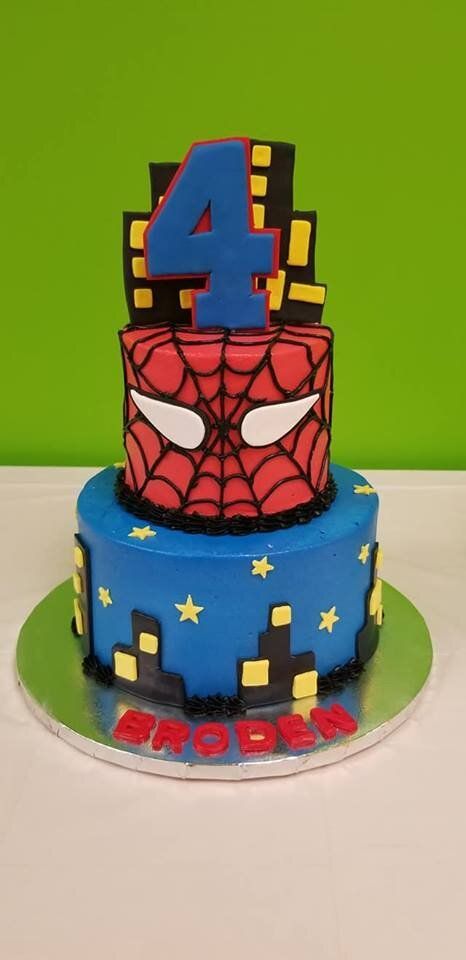 A spiderman cake with the number four on top of it.