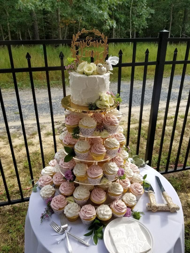 A wedding cake stacked on top of cupcakes on a table.