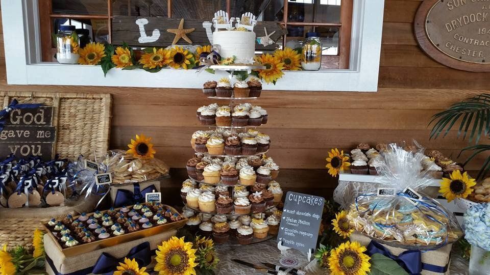 A table decorated with sunflowers and cupcakes for a wedding reception.