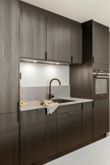 A kitchen with dark wooden cabinets and a sink.