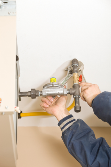 A man is fixing a gas pipe with a wrench