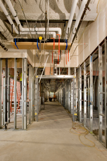 A hallway in a building under construction with pipes hanging from the ceiling