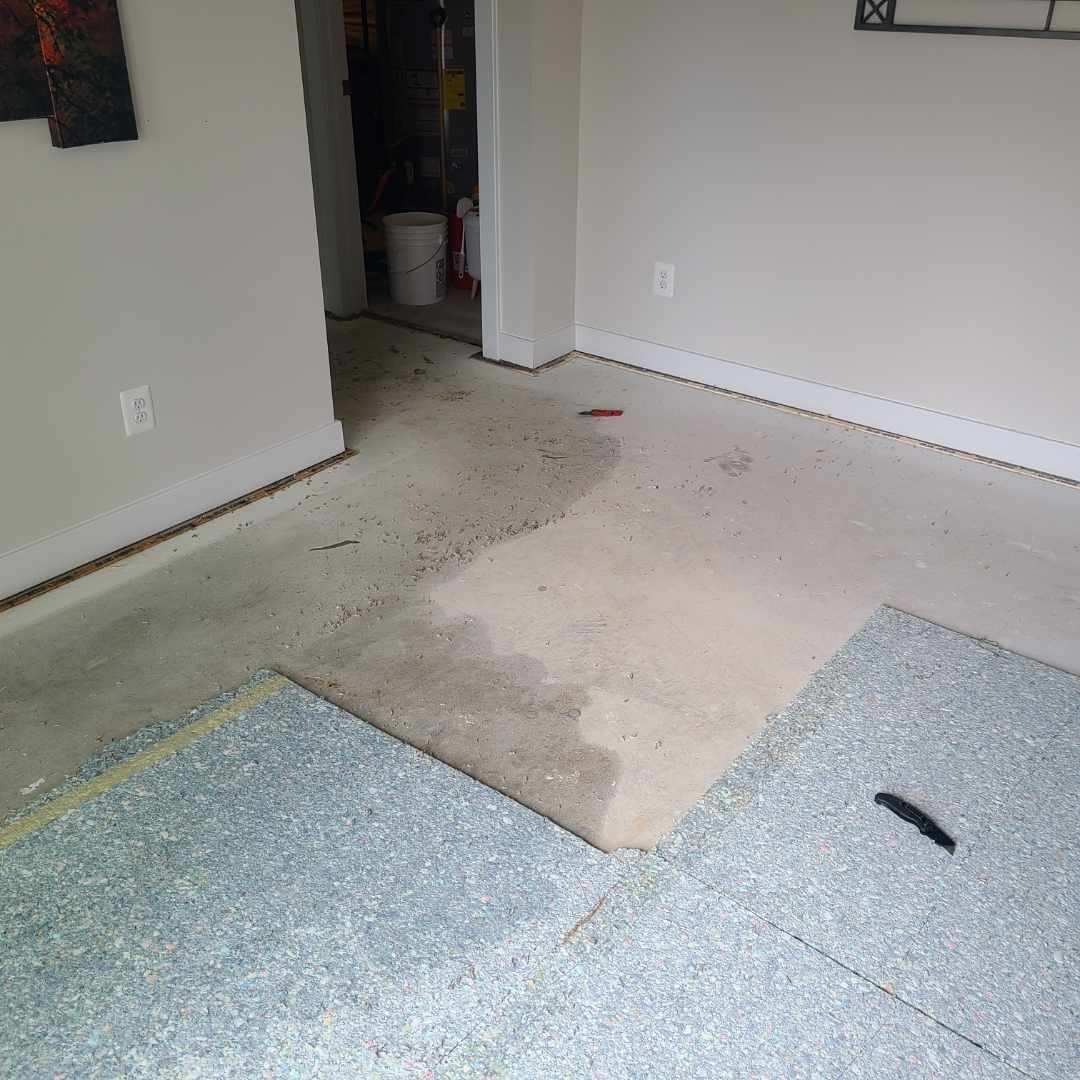 A room with a carpet on the floor and a measuring tape on the floor.