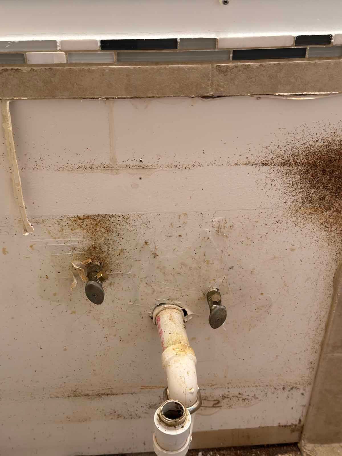 A close up of a dirty sink with a pipe coming out of it.