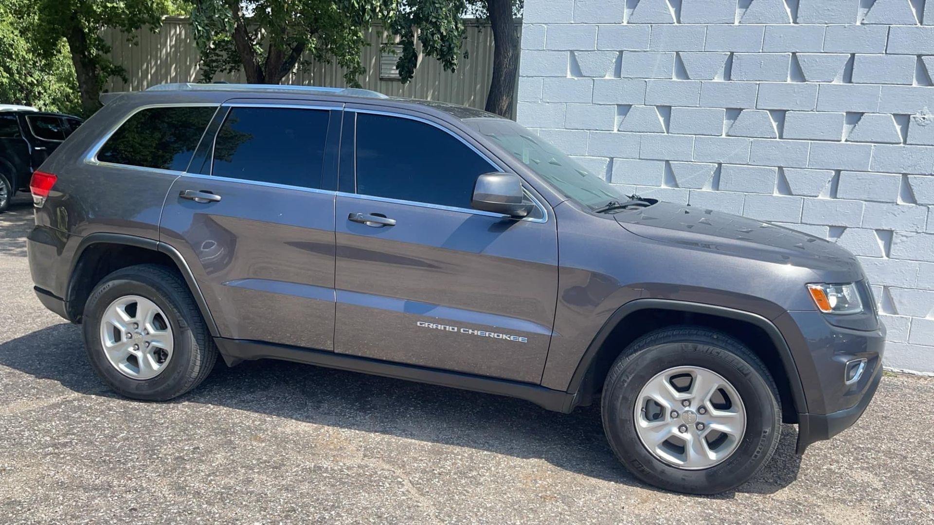A Gray Jeep Grand Cherokee Is Parked in Front of A White Brick Wall | Wichita, KS | ICT Pros Window