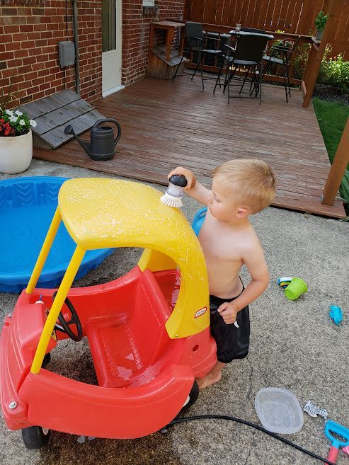 A 2 year old going through the steps to wash his car.