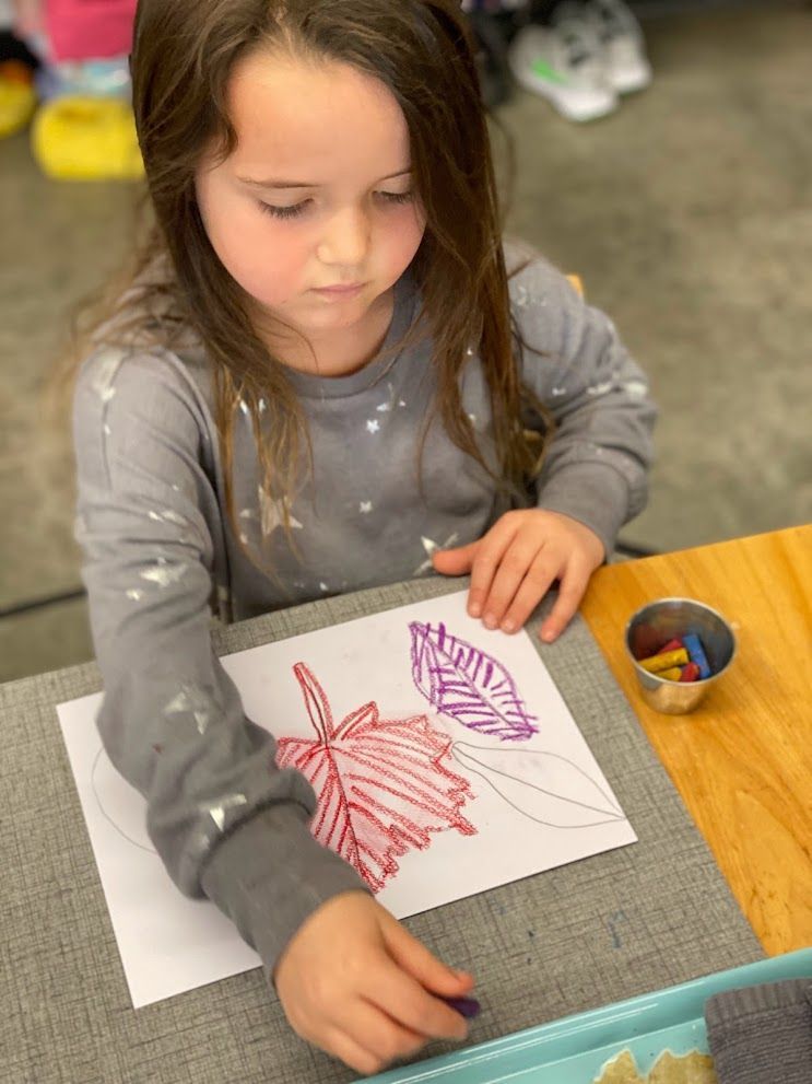 An IMA student works on leaf drawings.