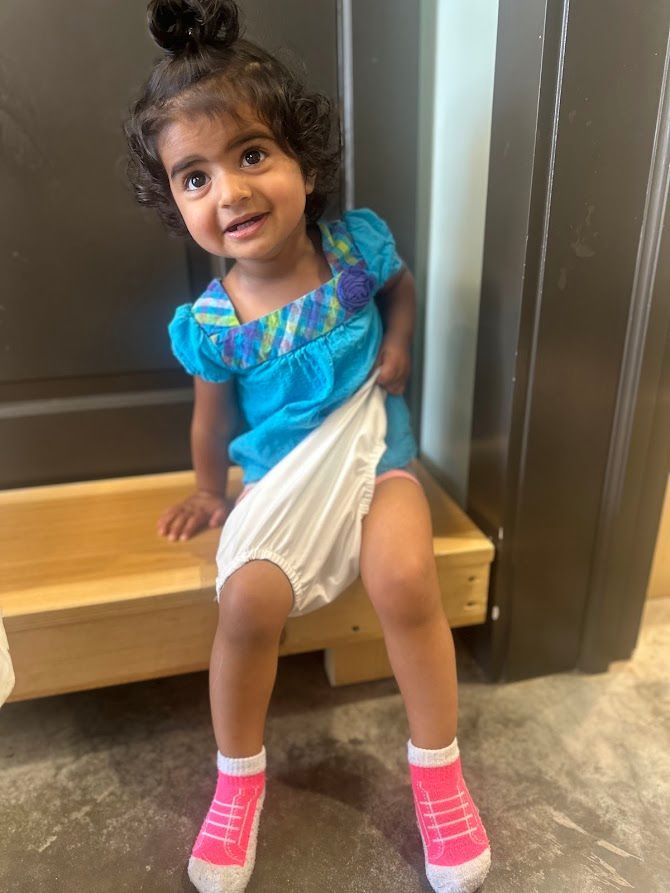 An IMA toddler pulls on her plastic cover.