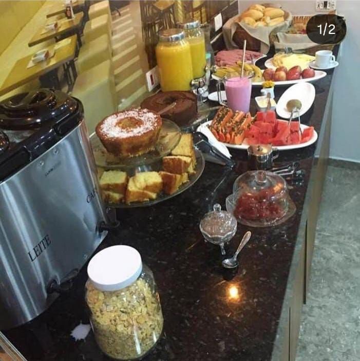 Buffet de café da manhã com diversas opções de alimentos dispostas em um balcão.