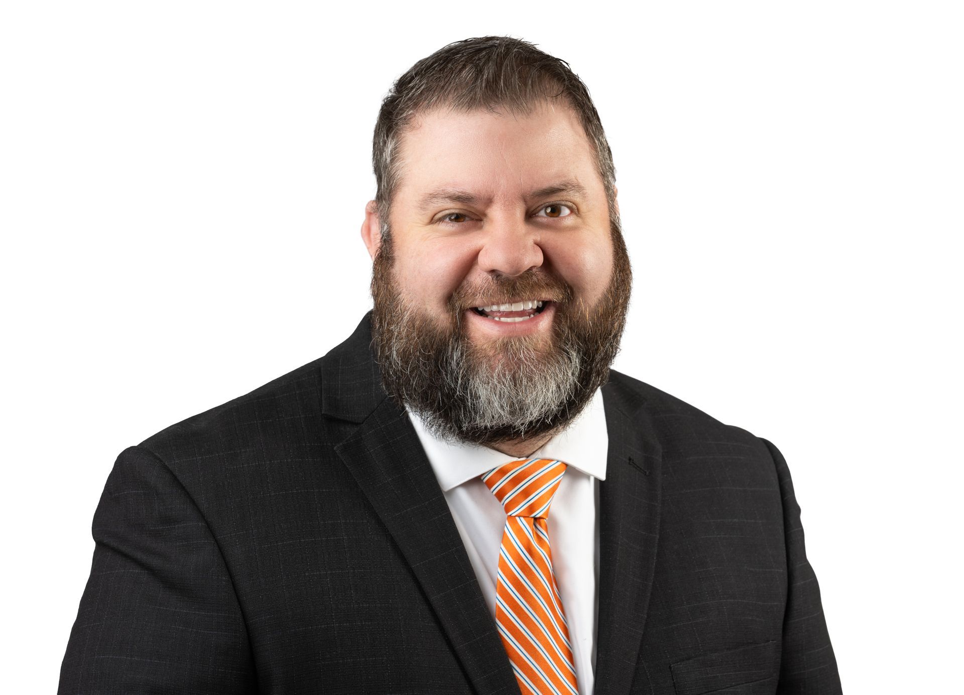 A man with a beard is wearing a suit and tie and smiling.