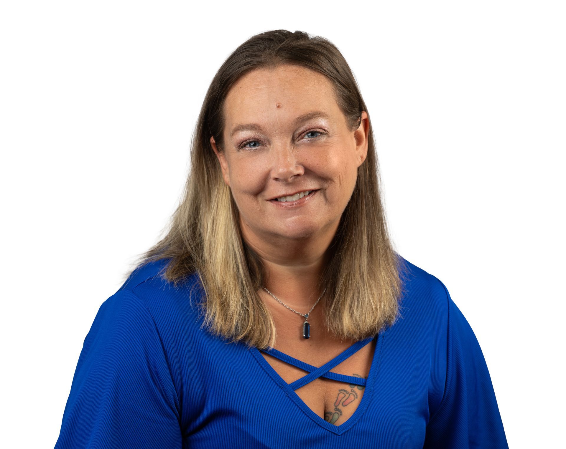 A woman wearing a blue shirt and a necklace is smiling for the camera.