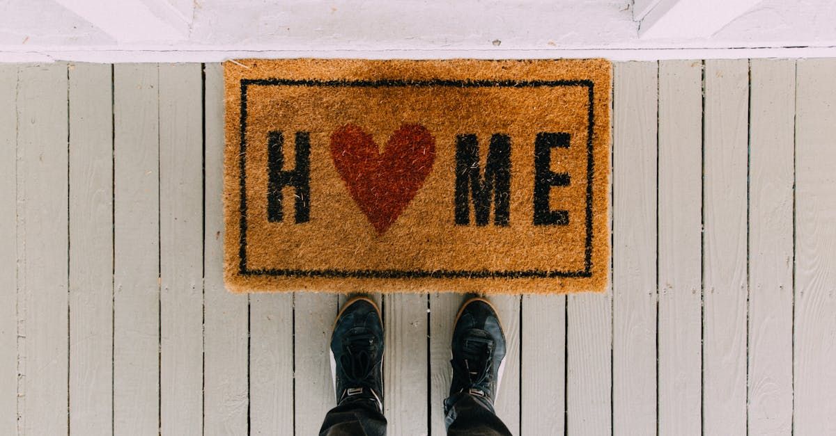 A person is standing on a door mat that says `` home '' with a heart on it.