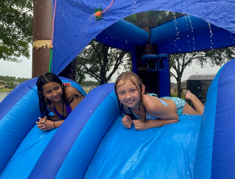 These girls are cooling off on a hot day with our water slide — Clermont, FL — Bouncin’ Back Party Rental