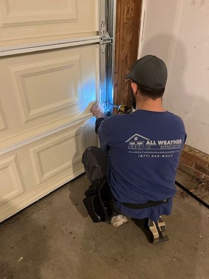 Technician adjusting garage door hinge during repair