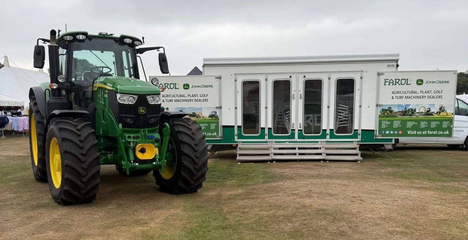John Deere tractor next to a mobile office at an outdoor event.