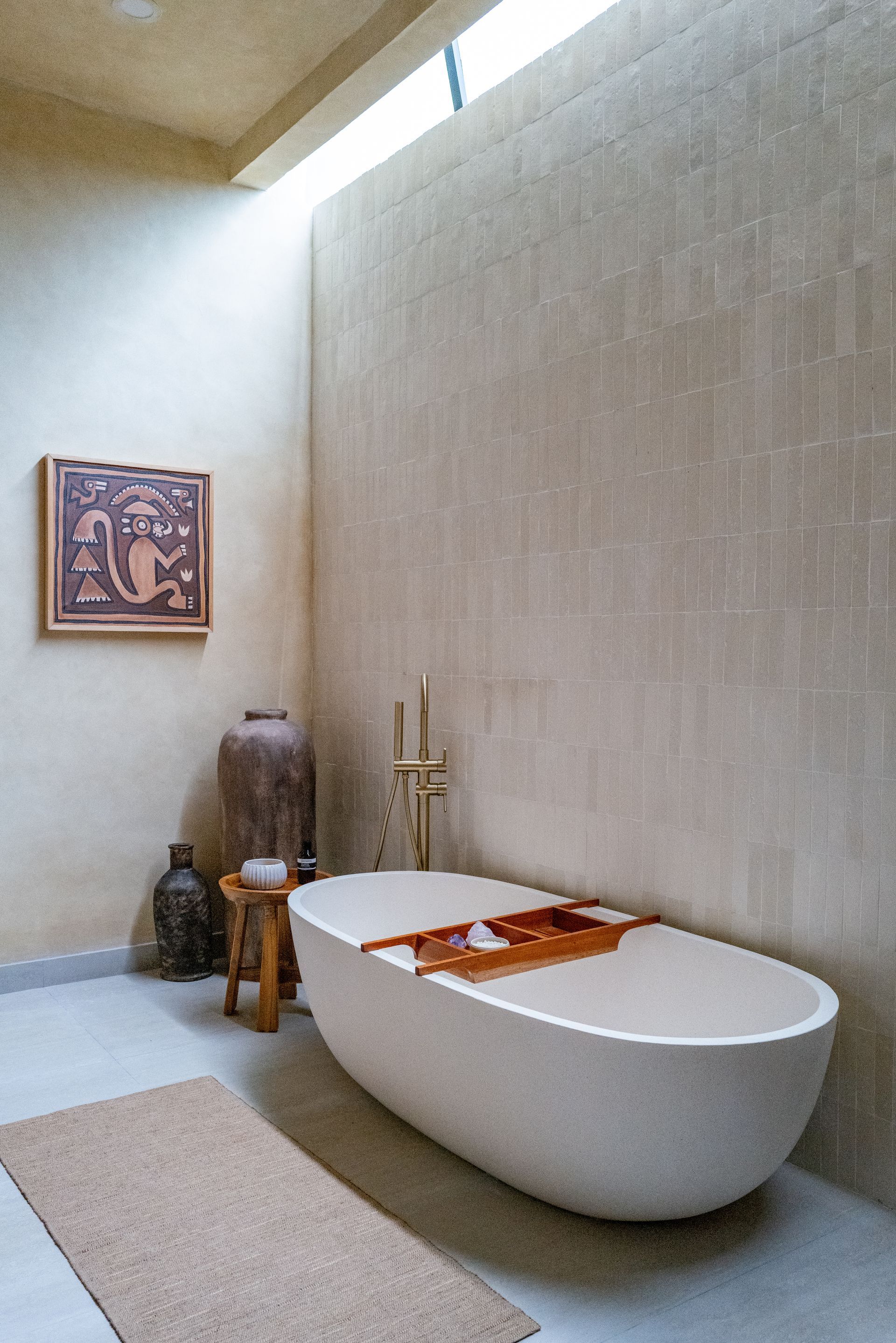 A modern bathroom with a white bathtub, light-colored walls, and a small rug on the floor.