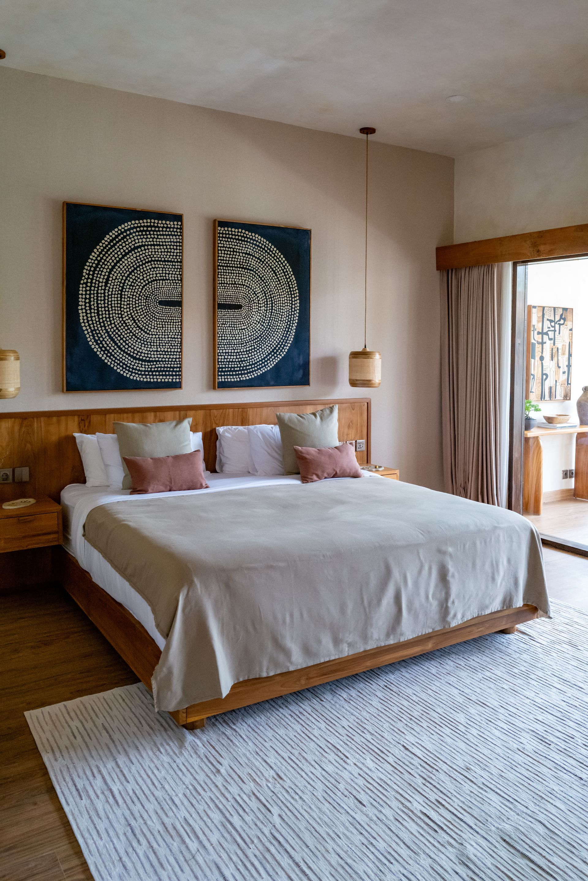 Bedroom with a wooden bed frame, neutral-colored bedding, and two circular wall hangings above the headboard.